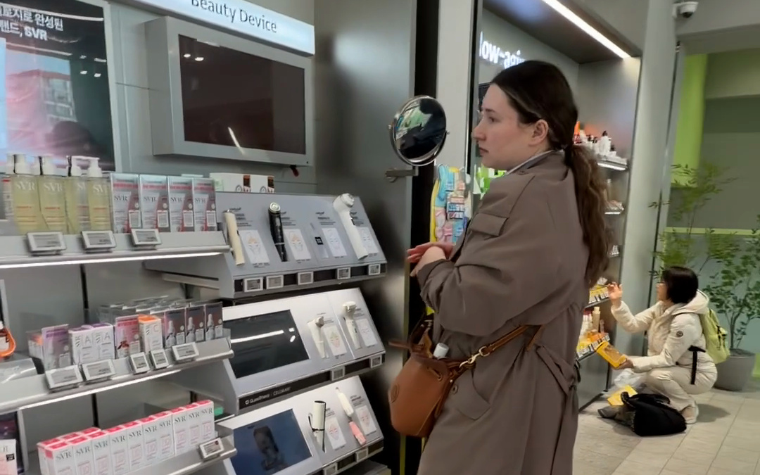 Two travelers picking skincare from the shelves of a Seoul beauty megastore